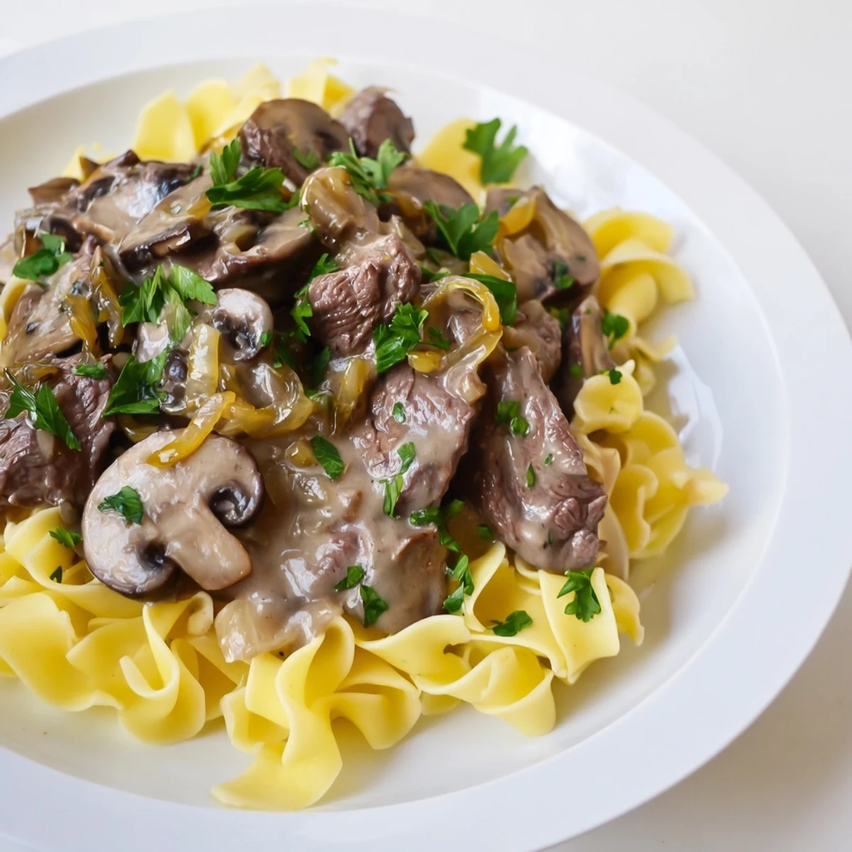 A close-up shot of steaming beef stroganoff: a savory sauce and tender beef.