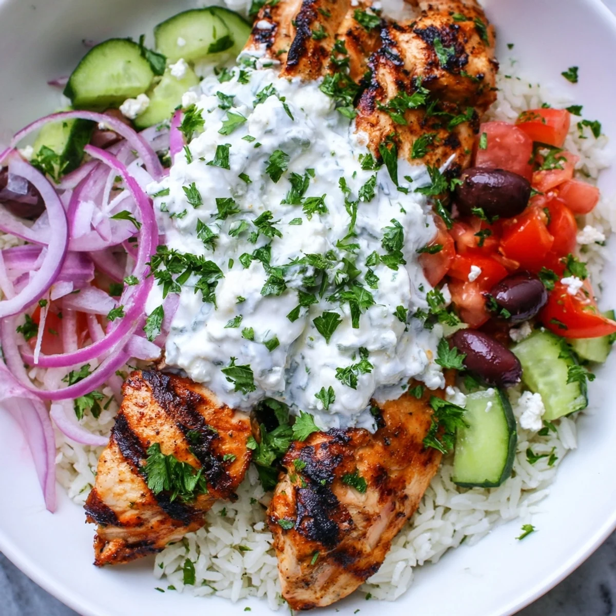 A delicious bowl of Greek chicken gyro bowls with flavorful, marinated chicken and creamy tzatziki.