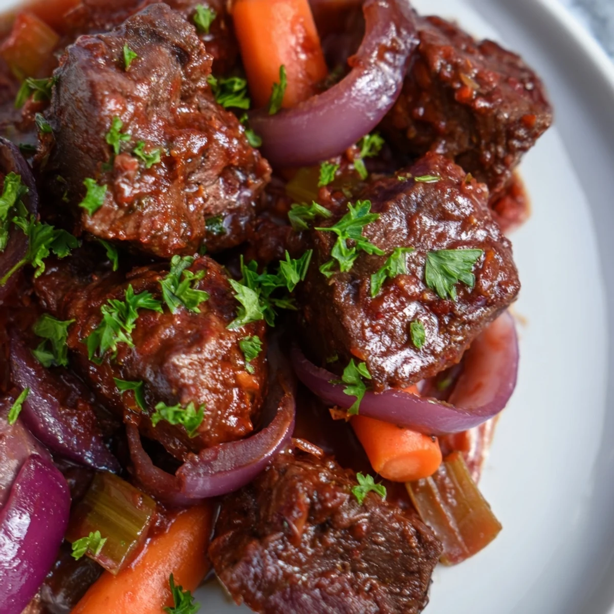 Golden brown beef chuck braised with sweet red onions in a rich, glossy red wine sauce, served over creamy mashed potatoes.