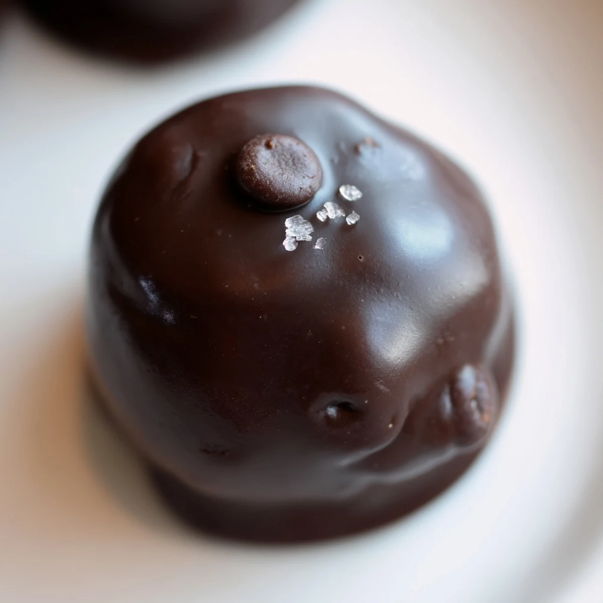 Close-up of Chocolate Chip Cookie Dough Truffles dipped in dark chocolate with mini chocolate chips peeking through.