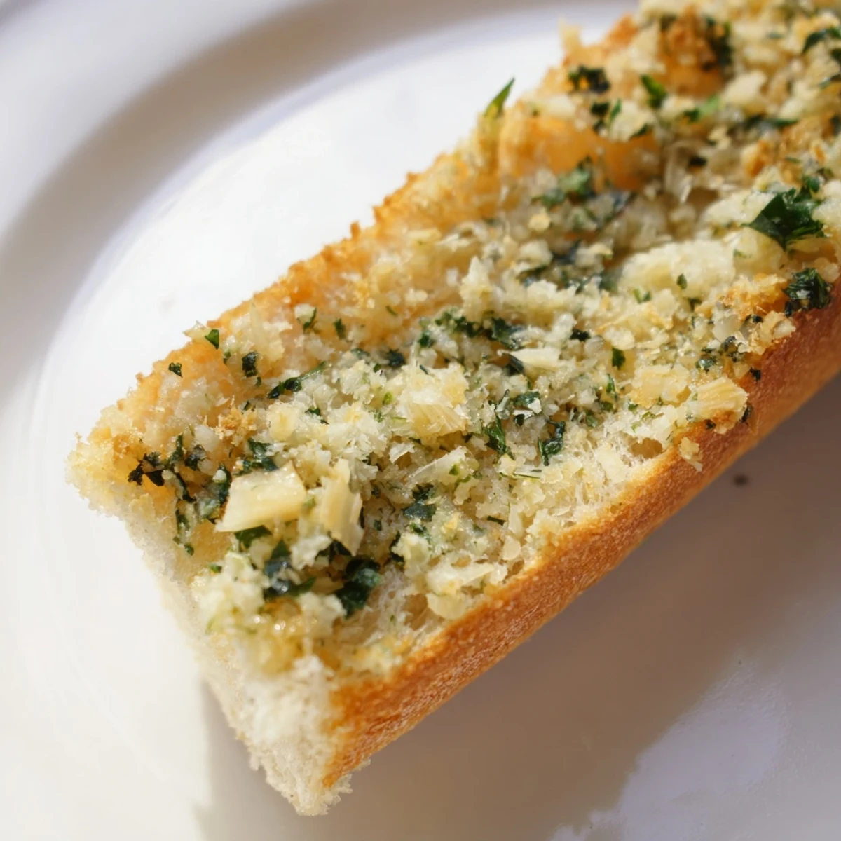 Freshly baked Garlic Butter French Bread sliced into warm pieces, showing rich garlic butter and parsley topping.