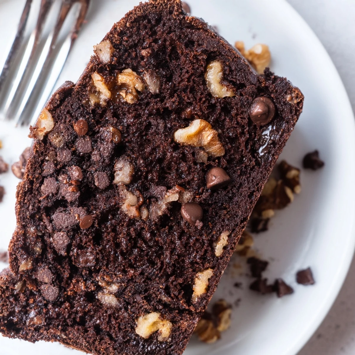 A freshly baked loaf of Chocolate Banana Bread with a cracked top, served warm with a dollop of whipped cream.