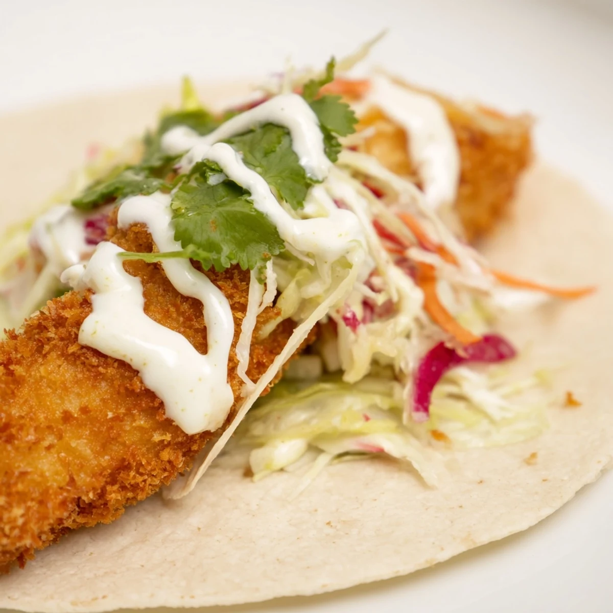 Golden-brown fillets tucked into warm tortillas with crunchy cabbage slaw and jalapeño slices for a zesty kick.