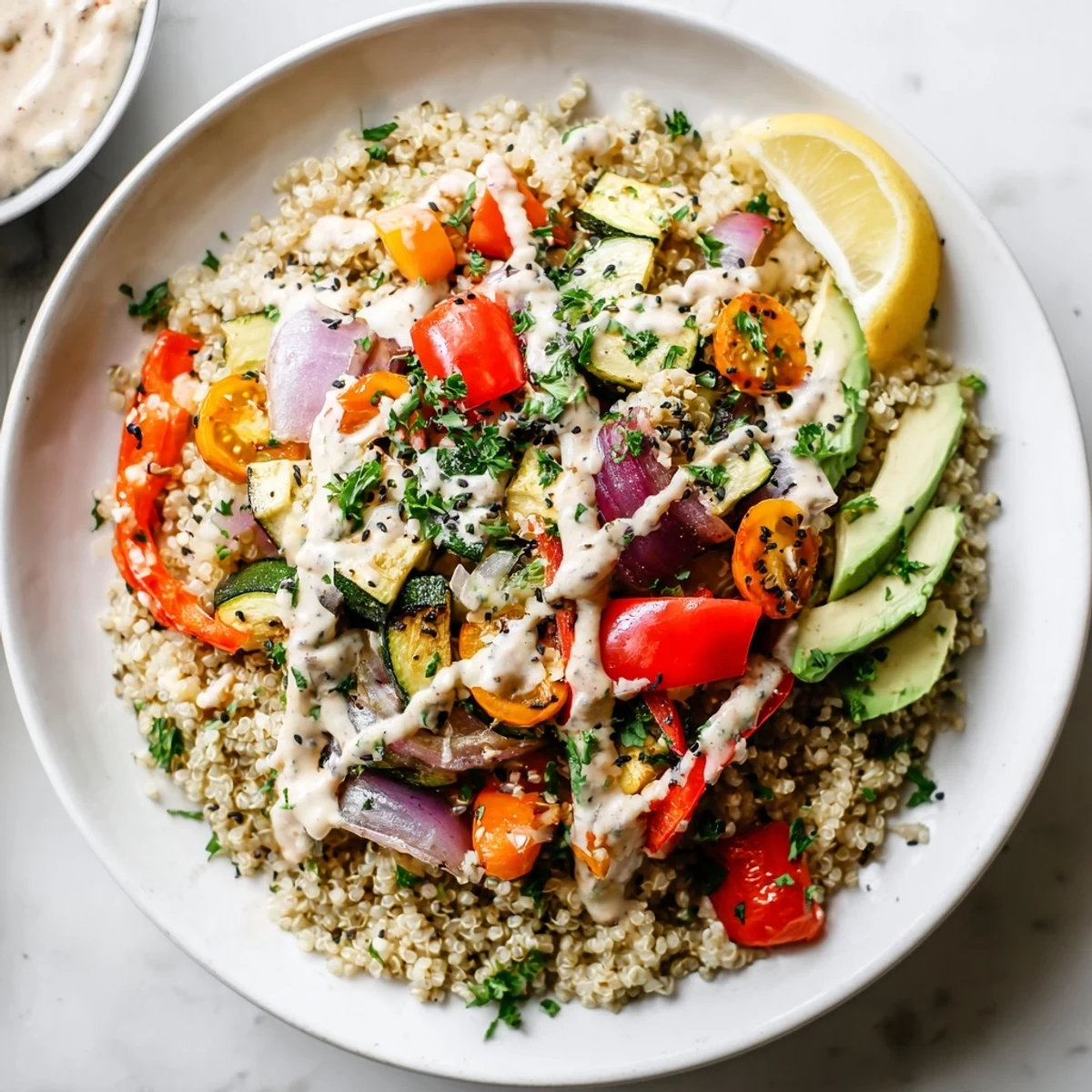 Healthy vegan quinoa bowl drizzled with lemony tahini dressing, garnished with parsley and sesame seeds for serving.
