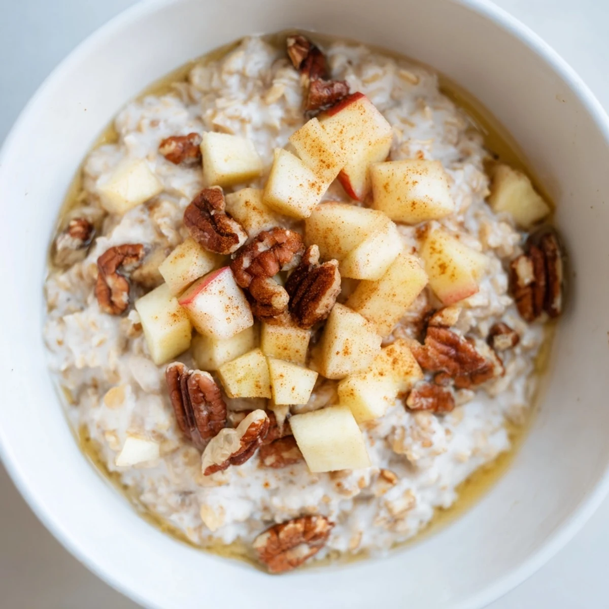 Creamy Warm Apple Cinnamon Oatmeal with Pecans served in a rustic bowl, highlighting cinnamon spices and hearty rolled oats.