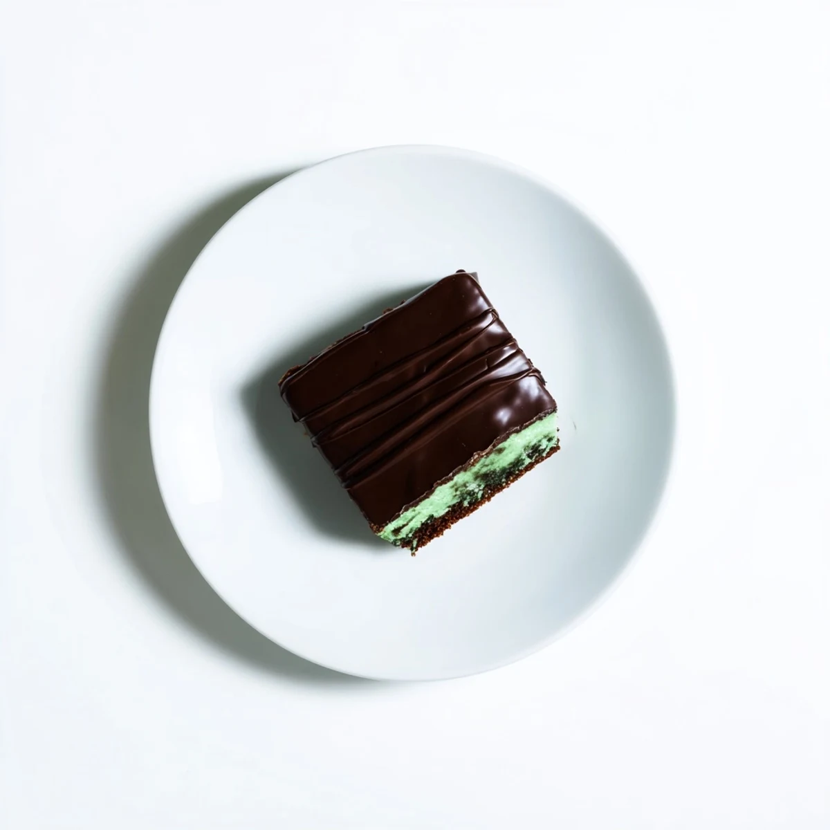 A dessert platter featuring Green Mint Brownies with Ganache, topped with a shiny chocolate layer and a hint of minty freshness.