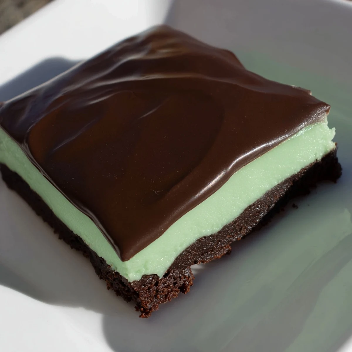 Stacked Shamrock Mint Brownies with Chocolate Ganache served on a plate with green mint sprinkles.