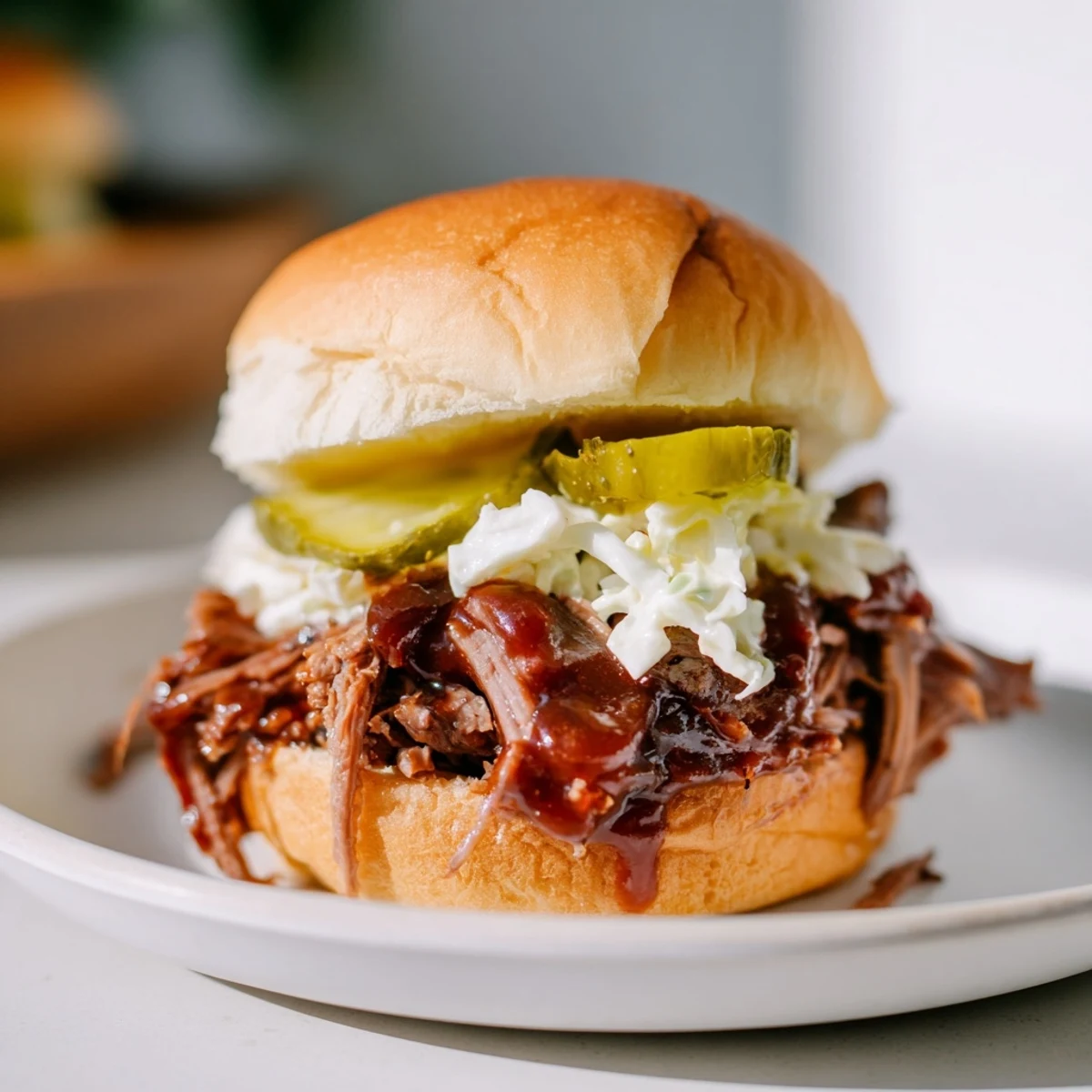 Golden slider buns stuffed with saucy shredded brisket, served with pickles and creamy coleslaw.