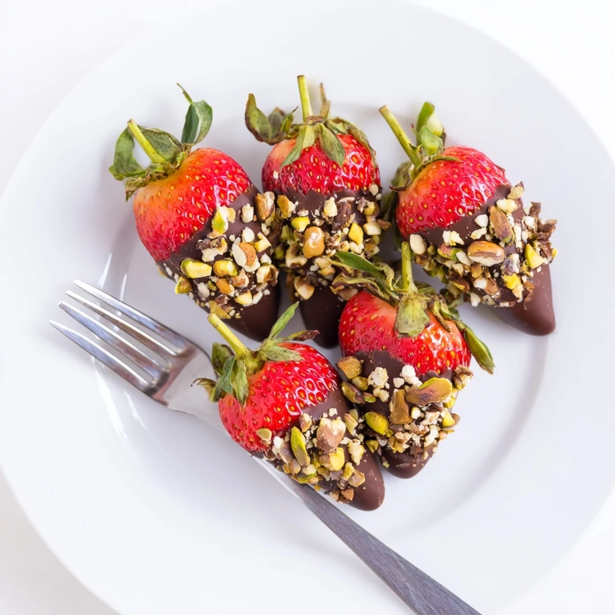 Savoring chocolate dipped strawberries with nuts, the glossy dark chocolate shell clinging to ripe red berries sprinkled with crunchy mixed nuts.  