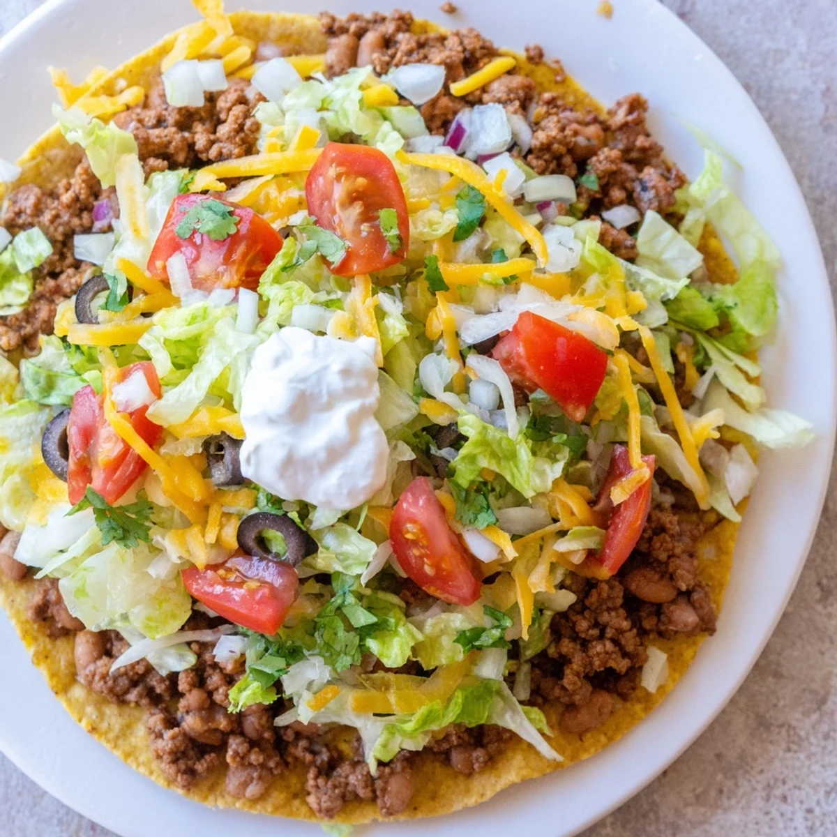 Beef Tostadas with Refried Beans served fresh with sour cream and lime wedges.