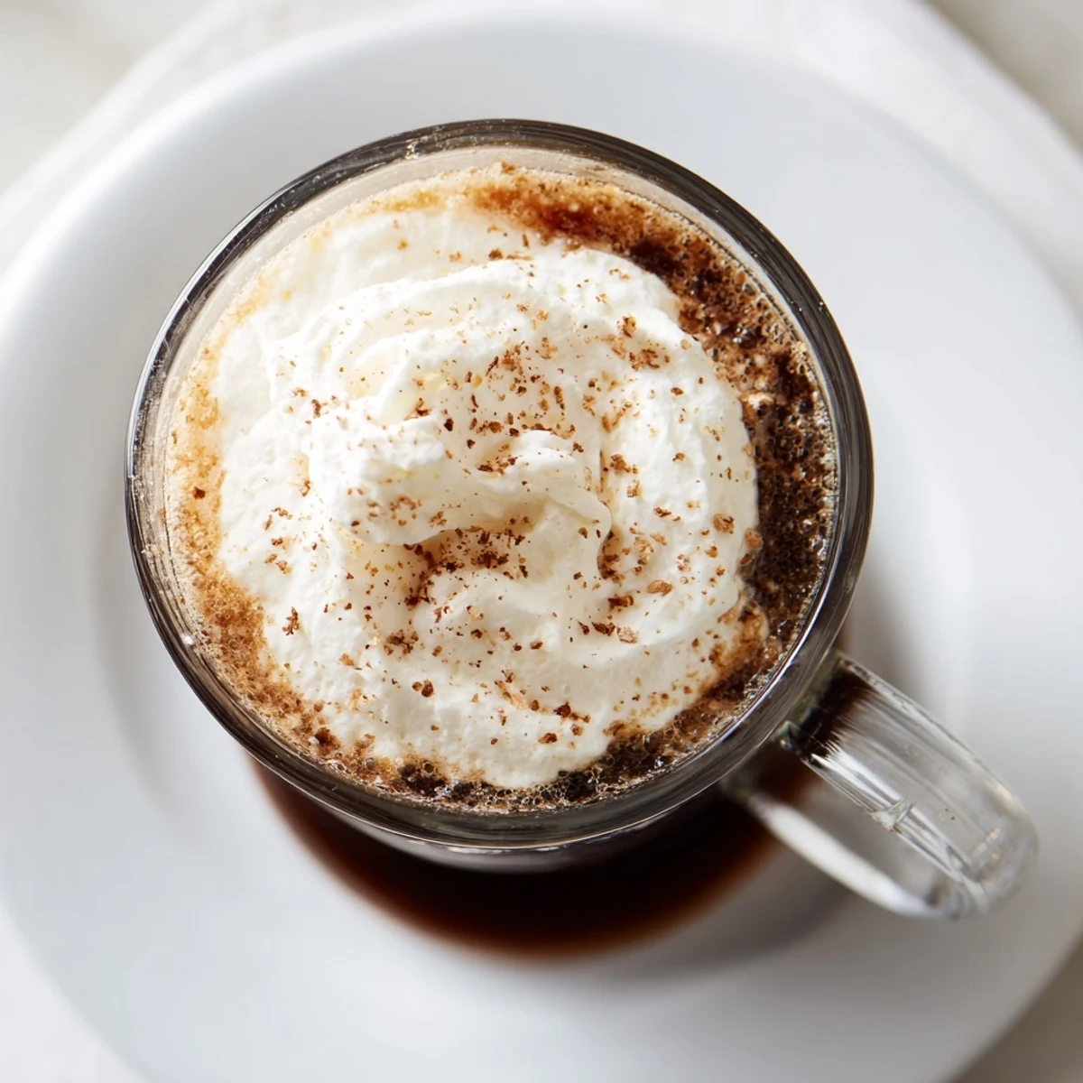A cozy Irish Coffee Mocktail with Whipped Cream served beside coffee beans and cinnamon sticks for warmth.