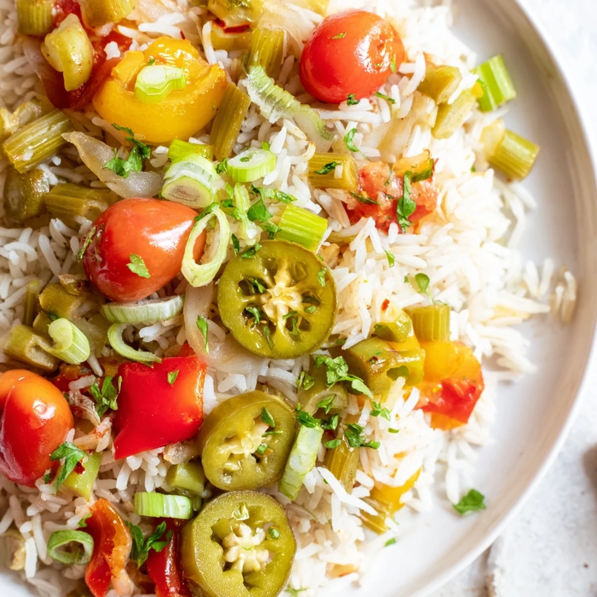 Steaming Mardi Gras Veggie Jambalaya garnished with green onions and parsley beside lemon wedges