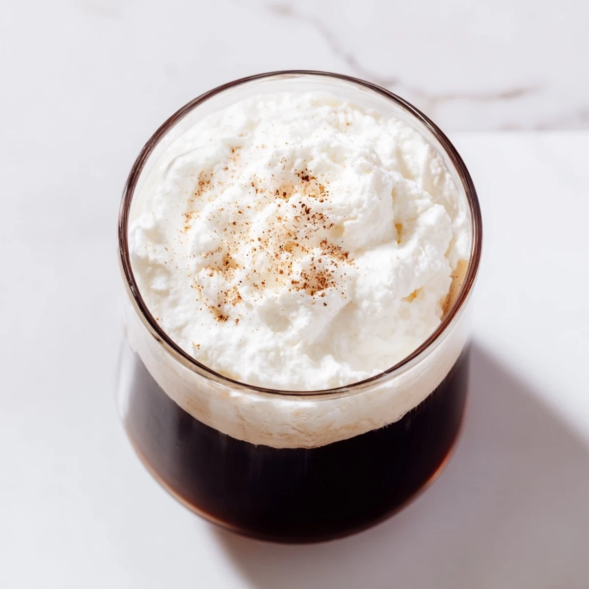 Hot Irish Coffee Mocktail with Whipped Cream steaming gently, served in a rustic mug beside scattered coffee beans and a cinnamon stick.