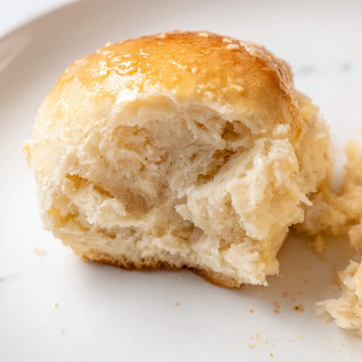 Warm, fluffy Best Vegan Dinner Rolls served on a rustic plate beside a bowl of soup.