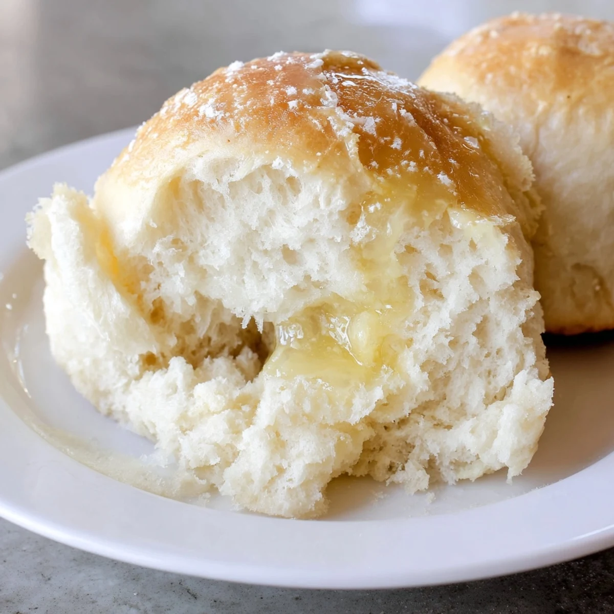 Freshly baked golden Best Vegan Dinner Rolls brushed with melted vegan butter in a baking dish.