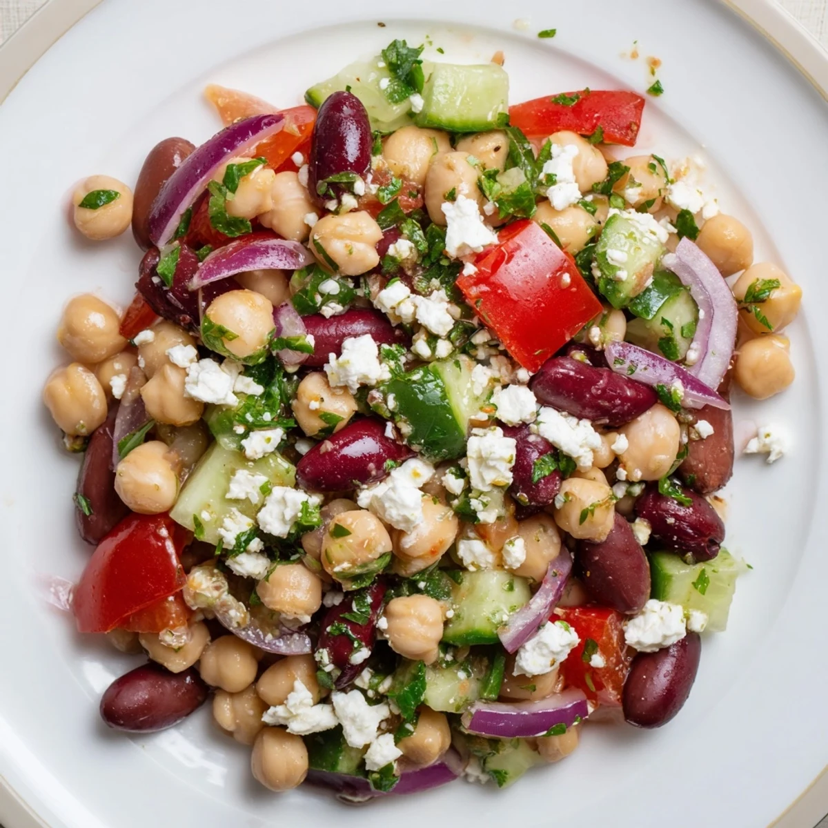 Mediterranean Dense Bean Salad tossed with diced red bell pepper, red onion, Kalamata olives, fresh parsley, and a bright lemon oregano vinaigrette, ready to eat.  