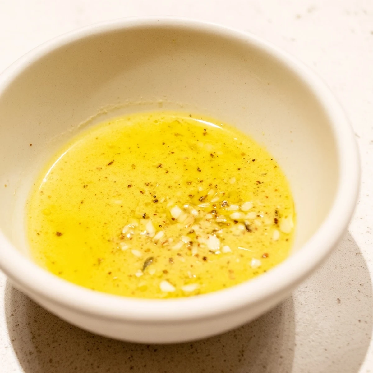 Homemade Lemon Dijon Dressing in a clear pitcher with a sprig of dill, set on a rustic wooden table.