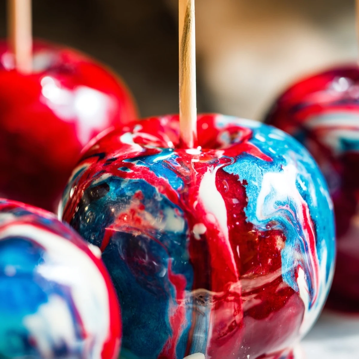 A glossy, marbled effect candy apple with vibrant red and blue swirls on a clean white plate.