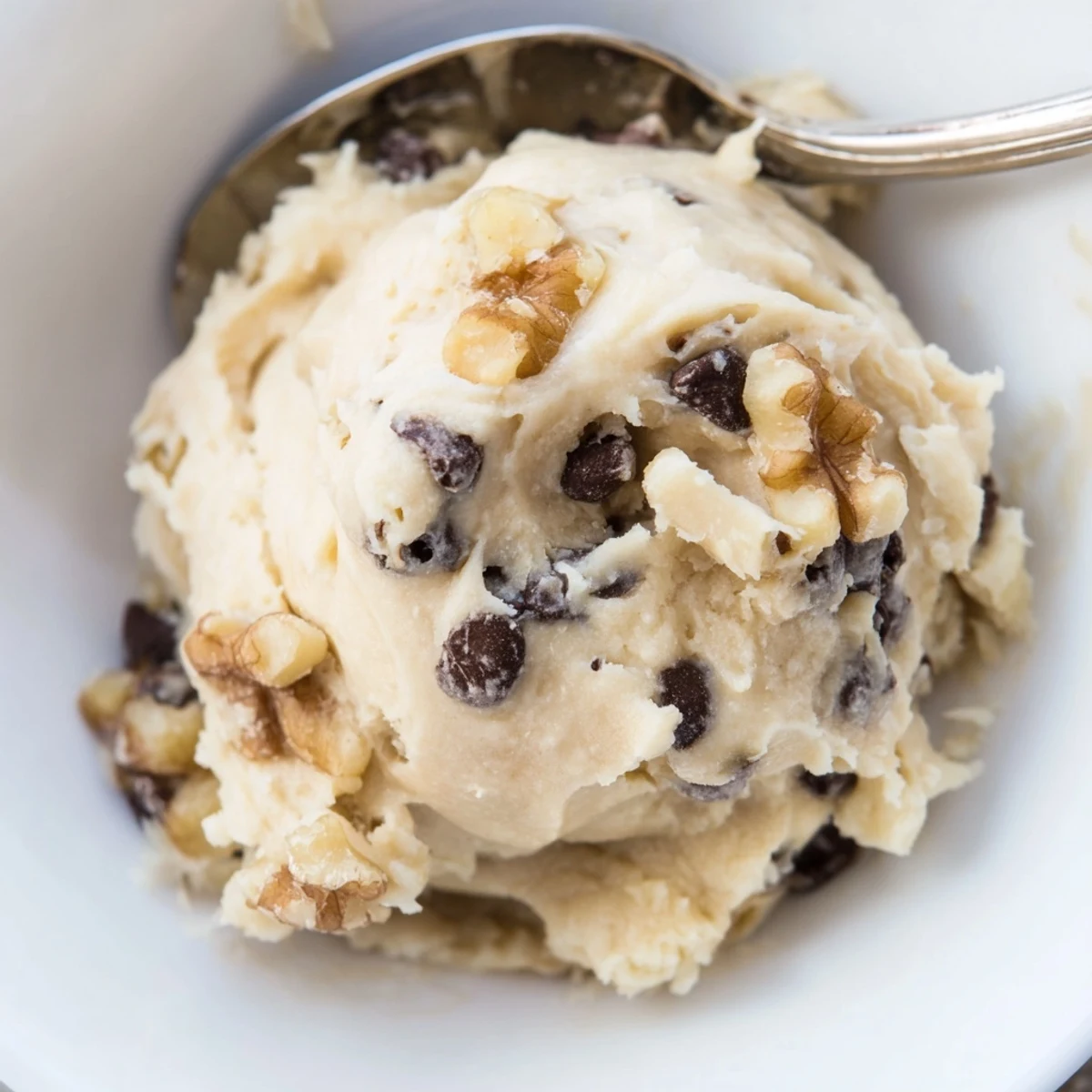 This close-up shows creamy Guilt Free Greek Yogurt Cookie Dough swirled in a bowl with peanut butter and mini white chocolate chips.