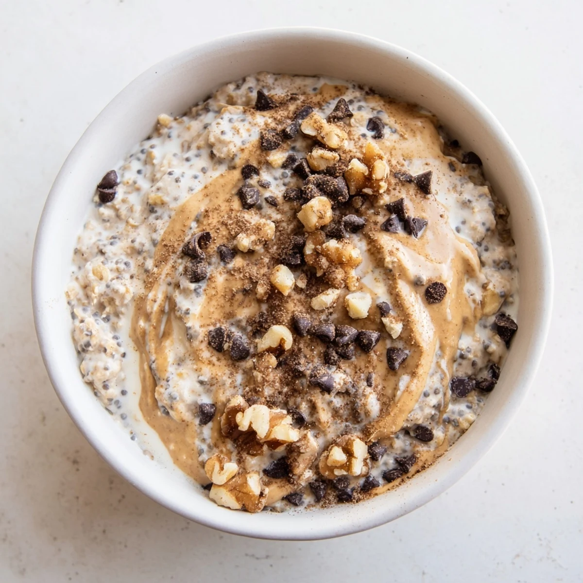 A jar of chilled Cookie Dough Overnight Oats with walnuts and a drizzle of nut butter.