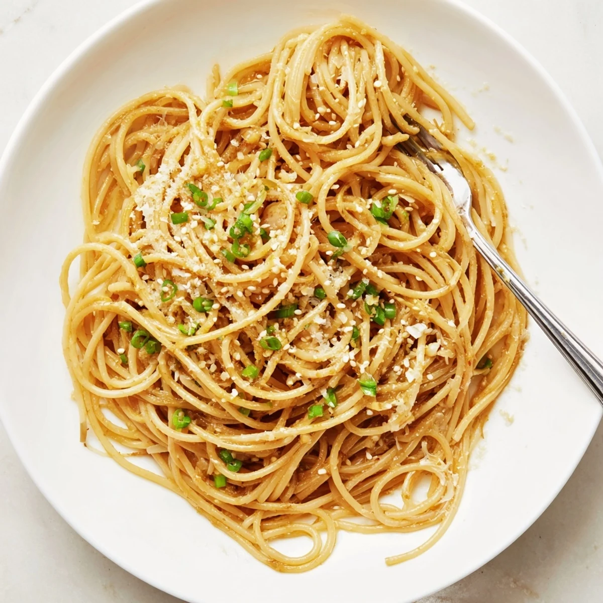Golden strands of Garlic Noodles tossed in a glossy buttery sauce, topped with fresh scallions and sesame seeds.
