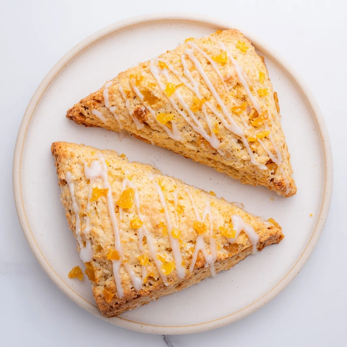 Freshly baked Candied Ginger Orange Scones paired with a cup of tea and a dollop of clotted cream on a rustic table.