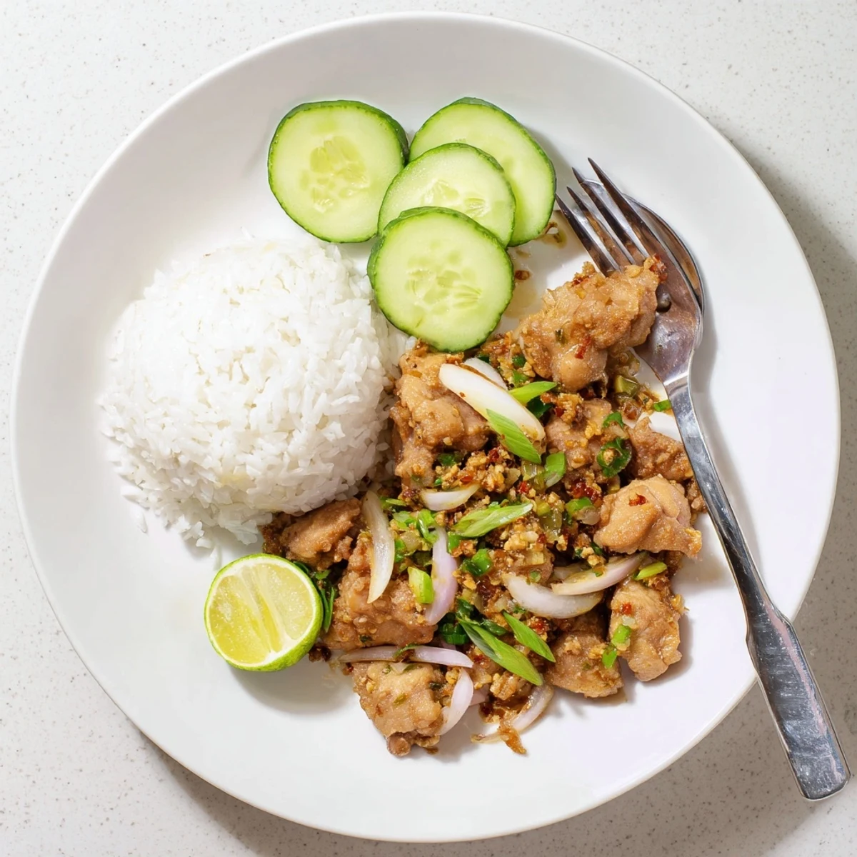 Sizzling Vietnamese Lemongrass Chicken in a skillet garnished with spring onions and lime wedges.