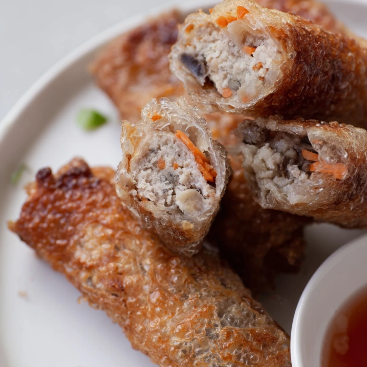 Crispy golden Cha Gio spring rolls filled with pork, shrimp, and vegetables served with herbs and dipping sauce.