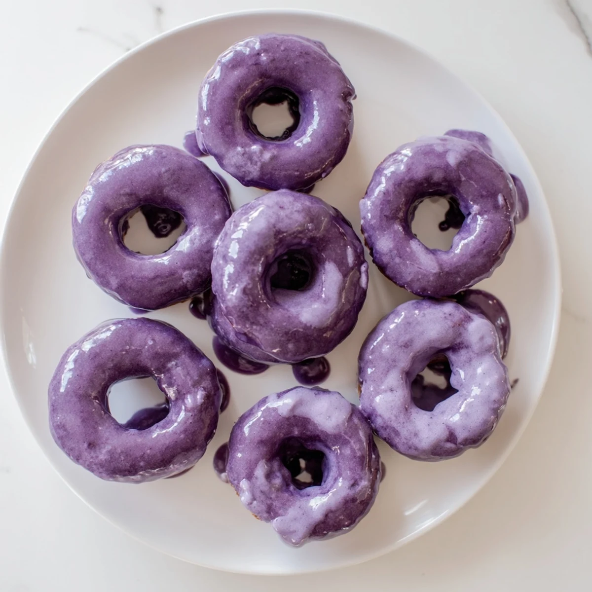 Glazed Ube Mochi Donuts stacked on a cooling rack, ready to be served with a hot cup of coffee.  