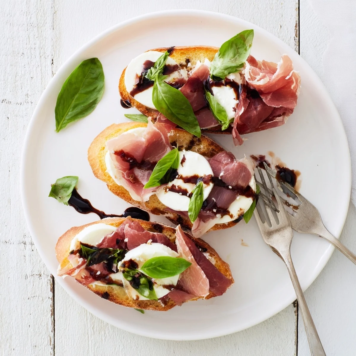 Golden toasted baguette slices hold melted mozzarella and prosciutto, drizzled with balsamic glaze for this Mozzarella Beef Prosciutto Crostini recipe.