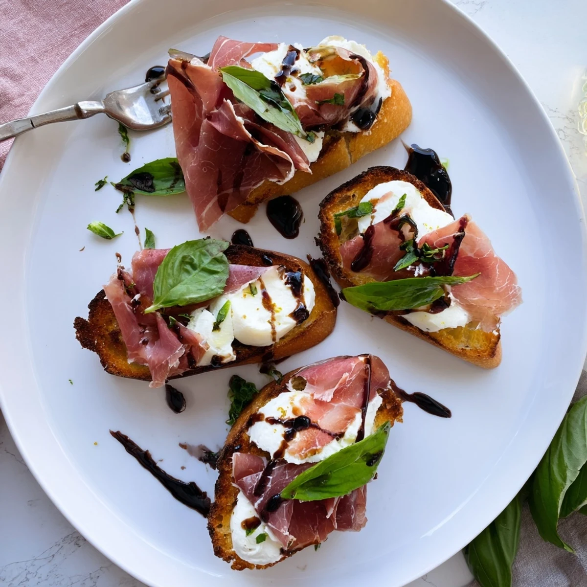 Enjoy warm Mozzarella Beef Prosciutto Crostini topped with creamy cheese, prosciutto, and balsamic glaze on a serving platter.