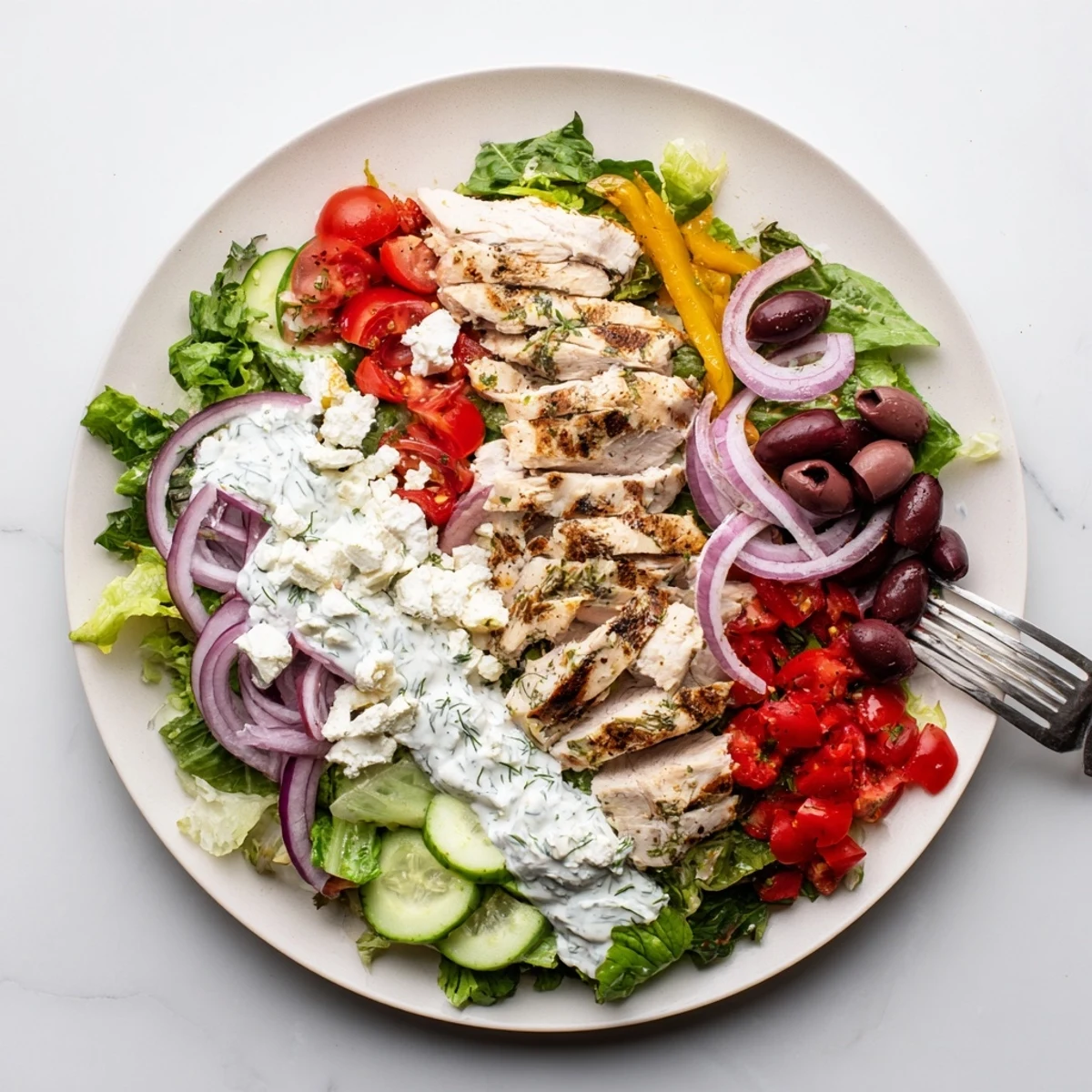 Freshly made Tzatziki Chicken Salad features crisp cucumbers, juicy tomatoes, and Kalamata olives in a vibrant bowl presentation.