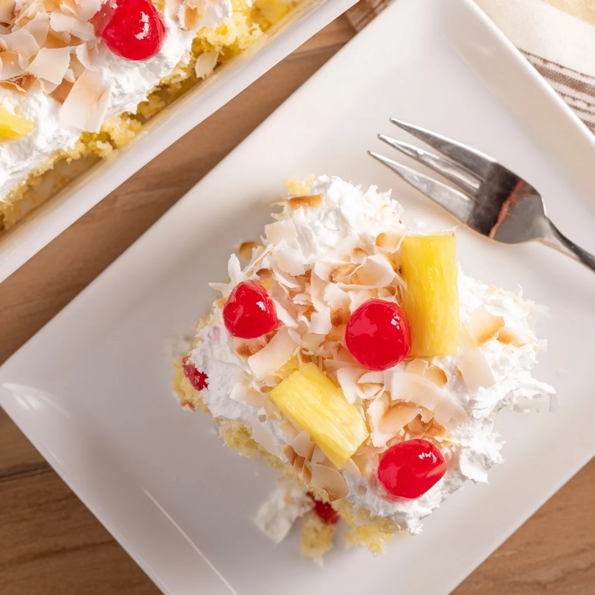 Golden Hawaiian Poke Cake topped with fluffy whipped cream and toasted coconut flakes