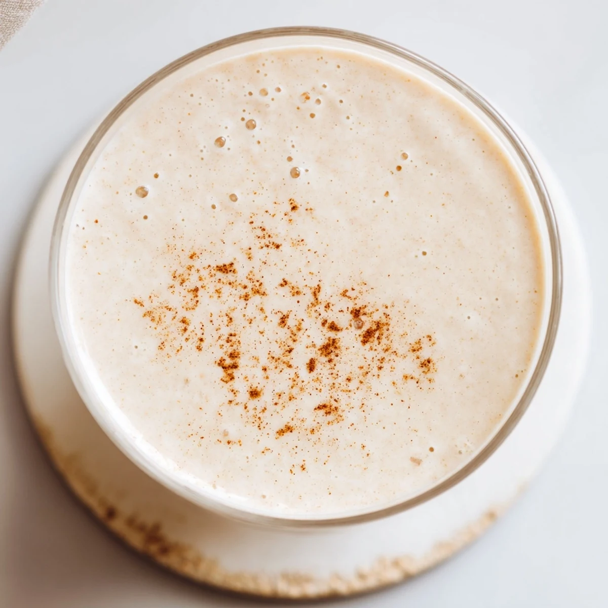 Creamy Greek yogurt banana smoothie poured into a glass topped with fresh banana slices