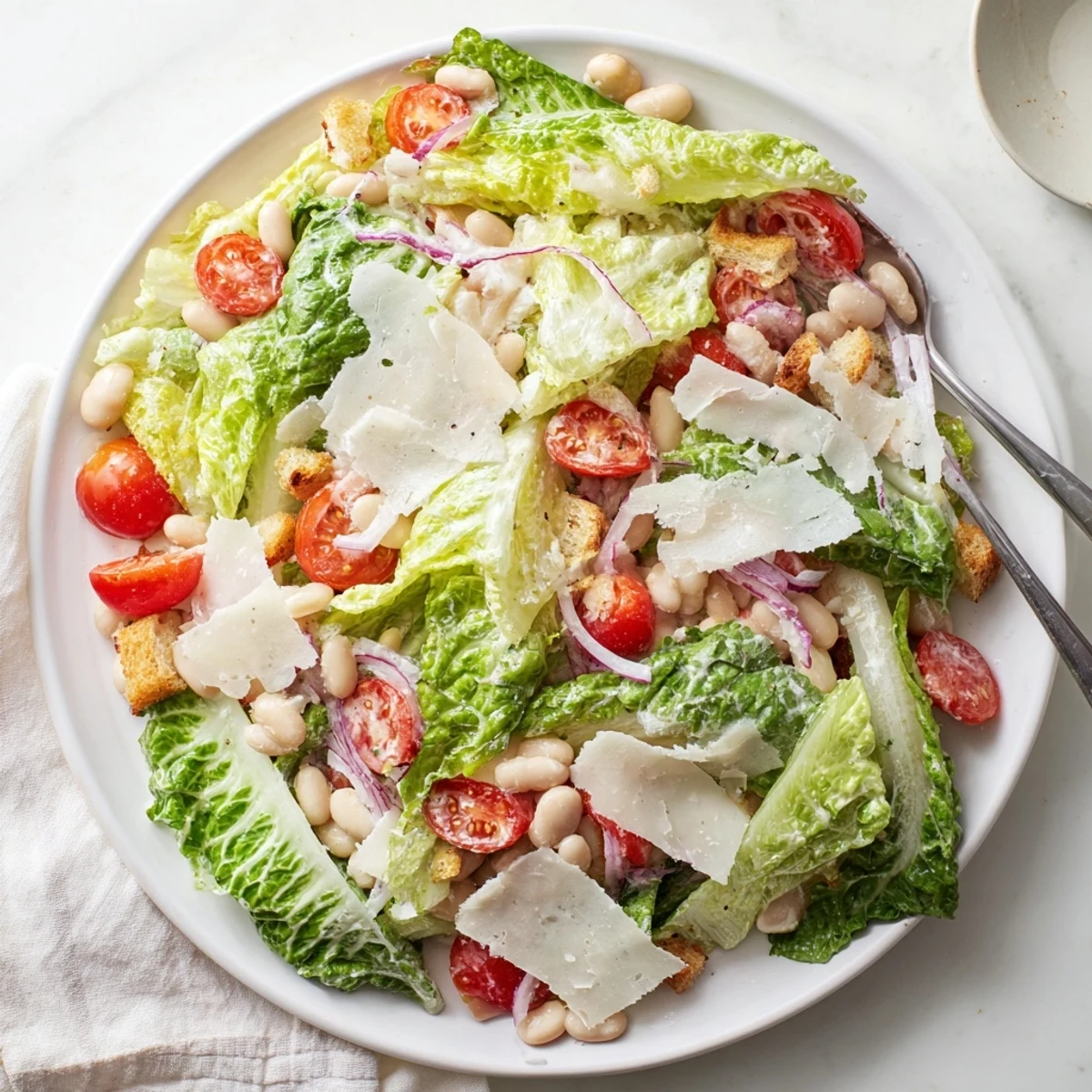 Protein-packed butter bean Caesar salad bowl featuring cherry tomatoes, red onion, and tangy homemade dressing