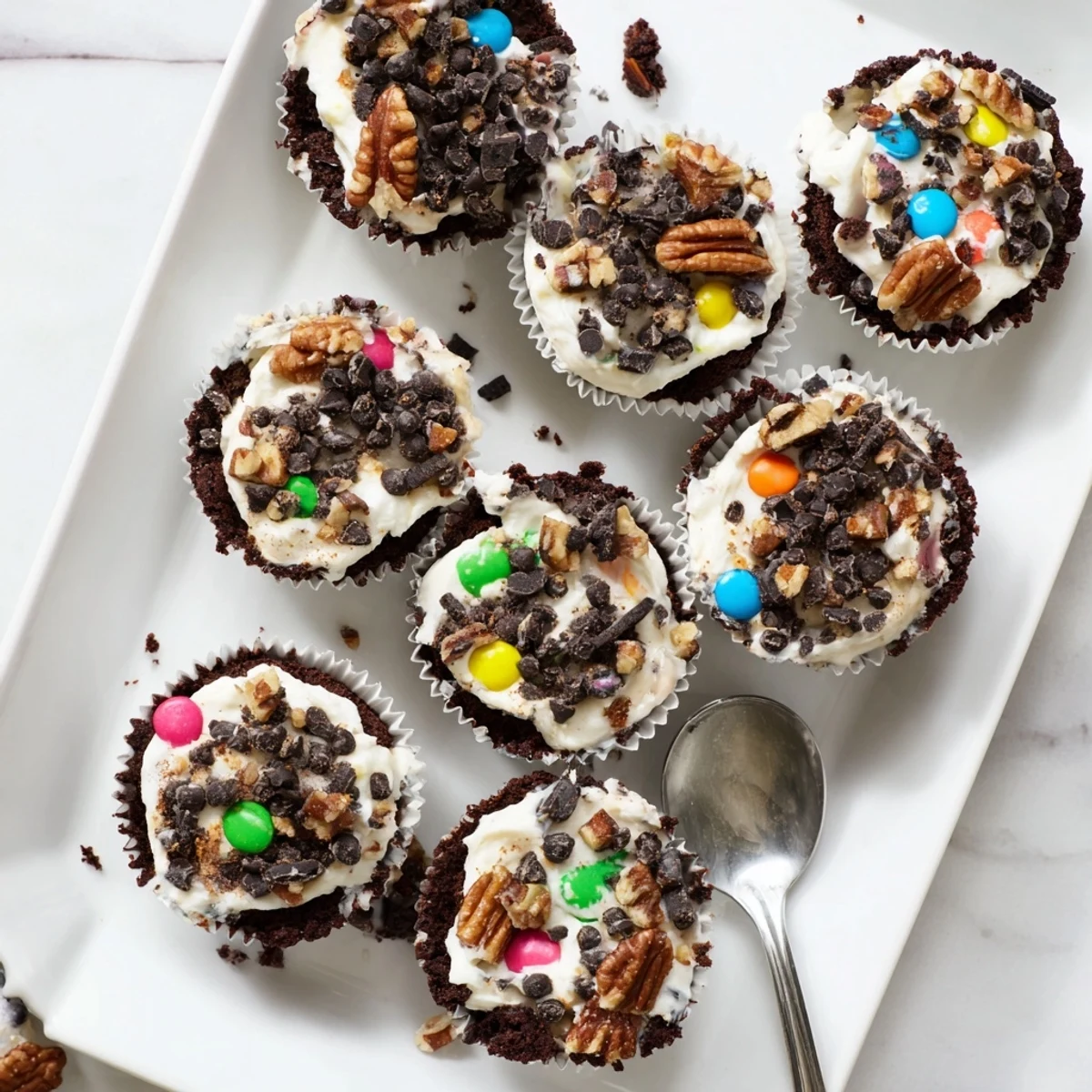 Decadent dessert showing layered cheesecake and brownie cups sprinkled with crushed cookies and nuts