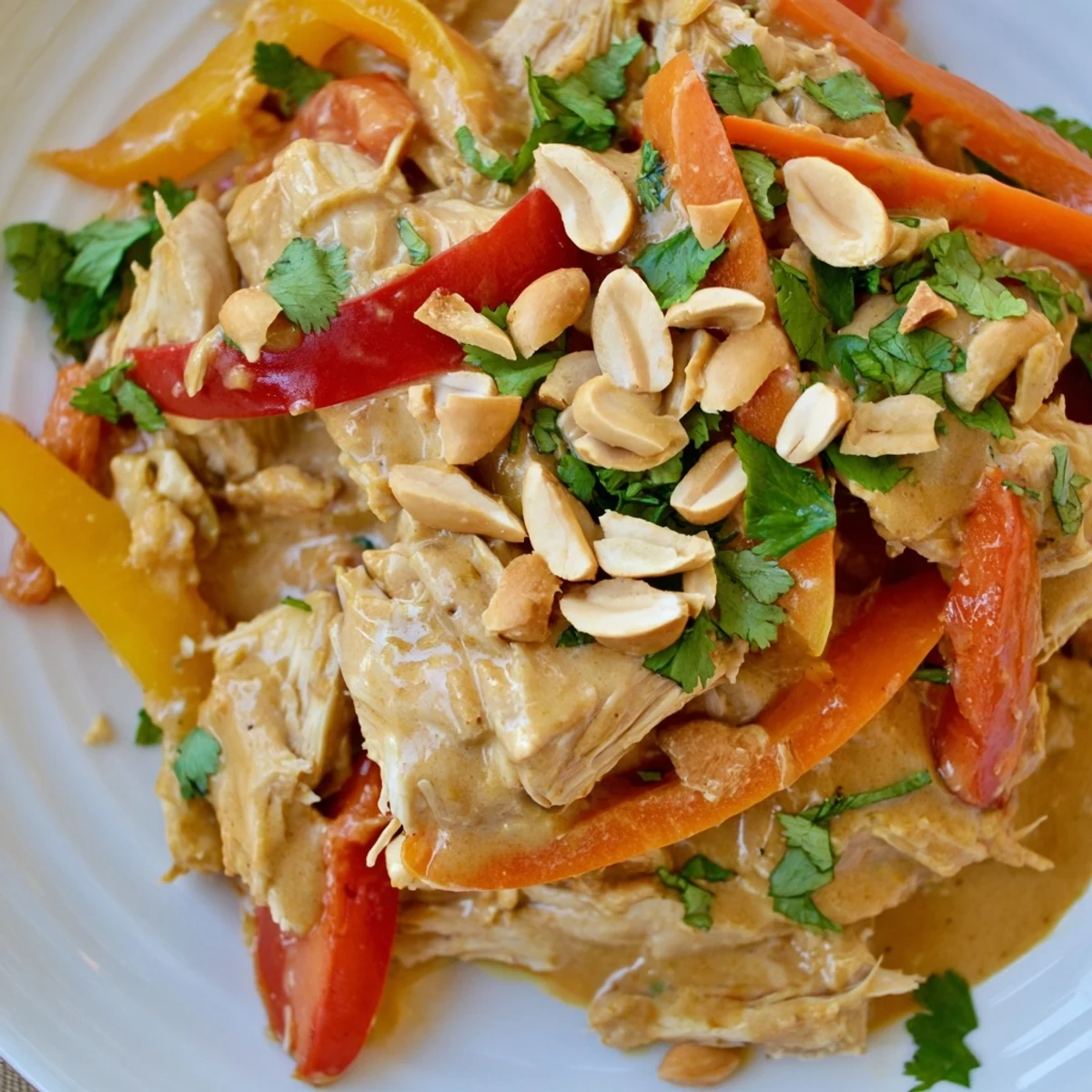 Creamy peanut sauce glazed slow cooker peanut chicken with colorful bell peppers and roasted peanuts