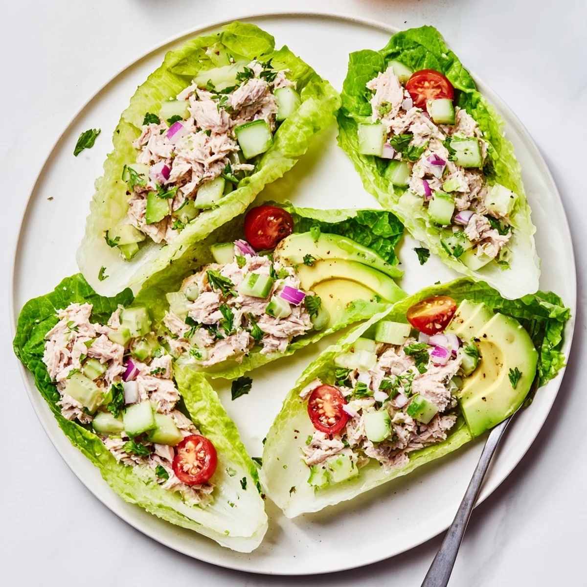 Light lunch of tuna salad nestled in butter lettuce with colorful tomato garnishes