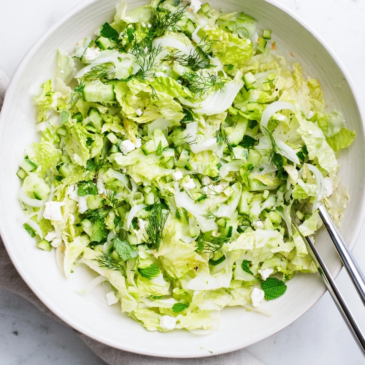 Vibrant Maroulosalata salad bowl showcasing green romaine, scallions, and crumbled feta cheese with zesty citrus dressing