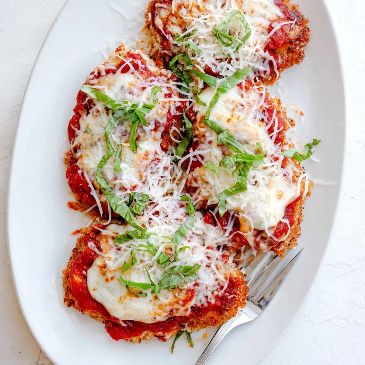 Baked chicken Parmigiana featuring juicy meat underneath melted cheese and low-carb Italian herb breading