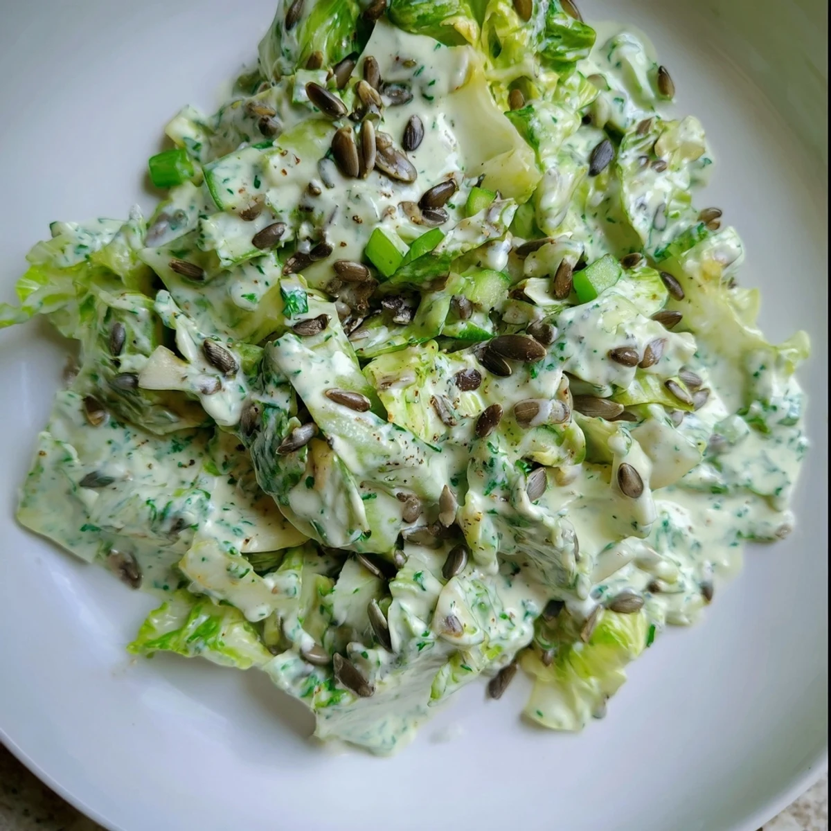 Vibrant Green Goddess salad bowl with crisp romaine, cucumber, and creamy herbed dressing sprinkled with roasted sunflower seeds