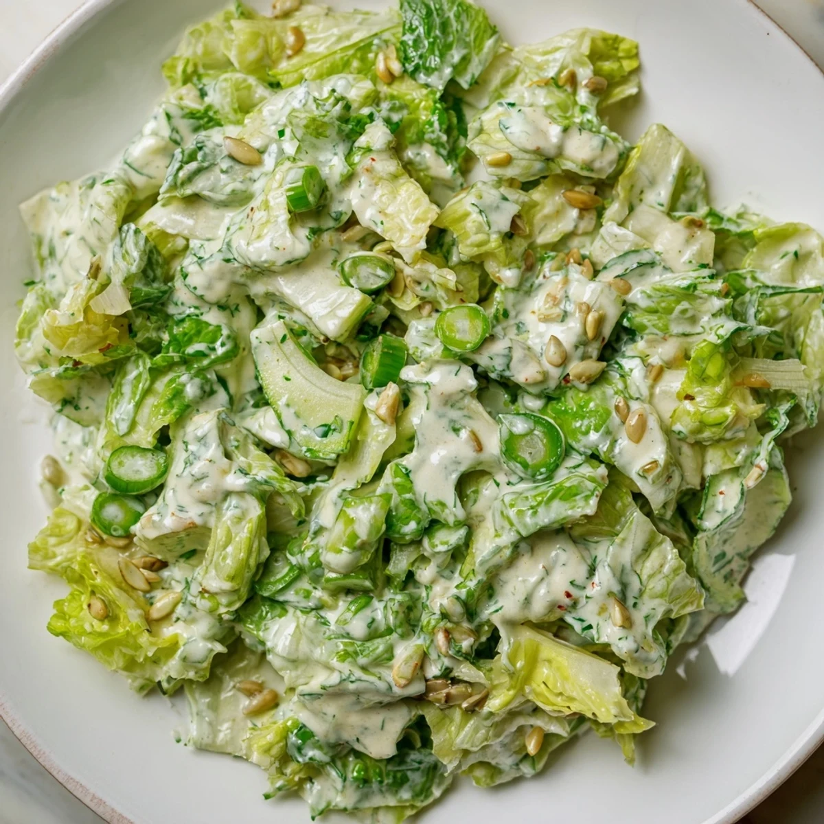 Fresh Green Goddess salad featuring chopped green cabbage, cucumber, and tangy yogurt dressing topped with crunchy pumpkin seeds
