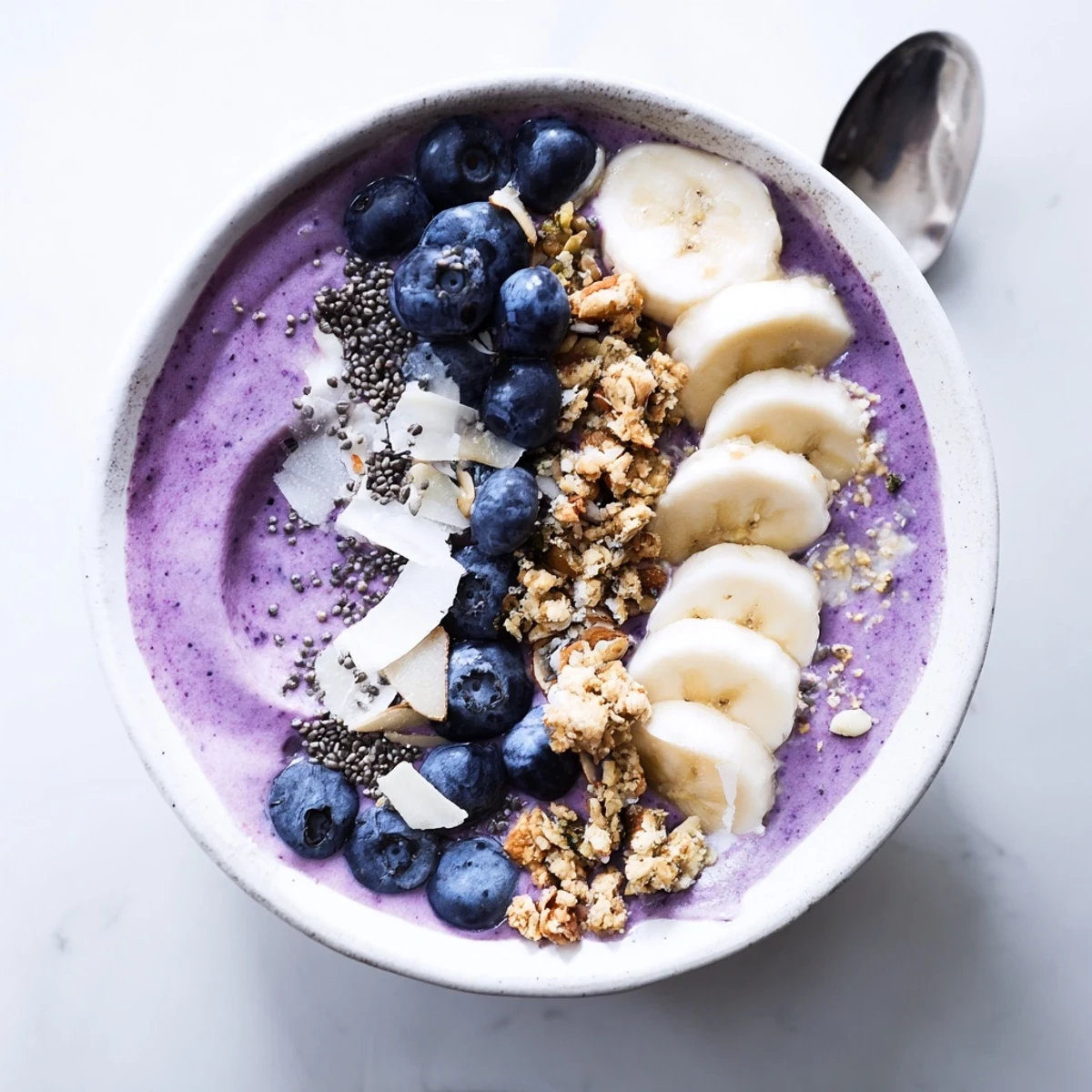 Vibrant breakfast smoothie bowl featuring blended blueberries and Greek yogurt decorated with colorful fruit and granola