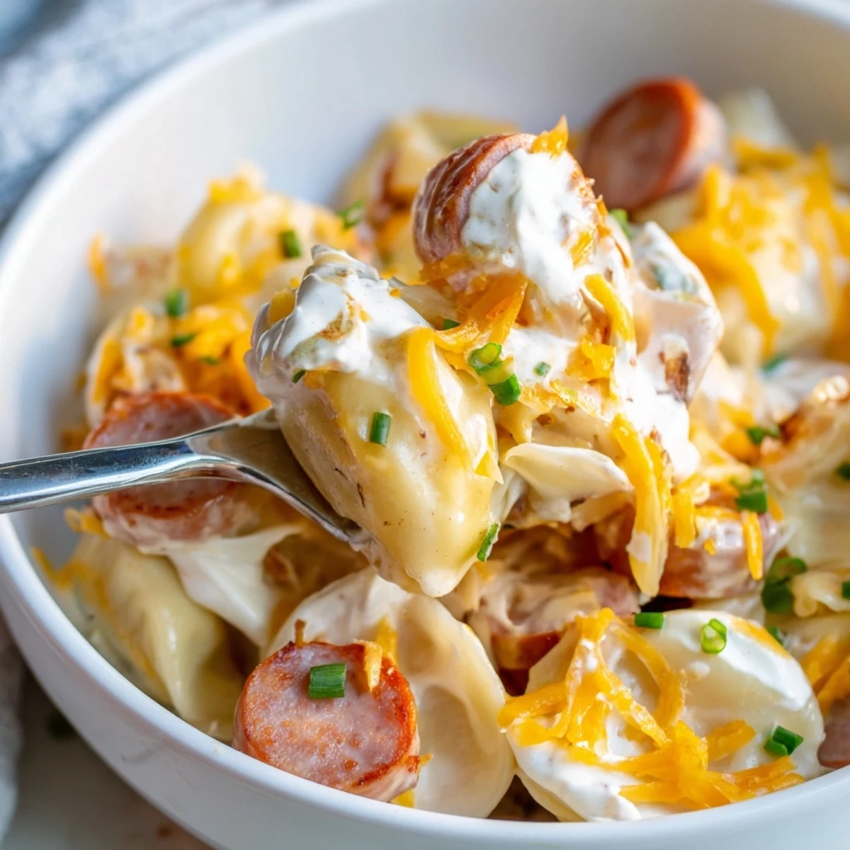 Creamy slow cooker pierogi casserole bubbling with cheese sauce, sliced sausage, and caramelized onion layers