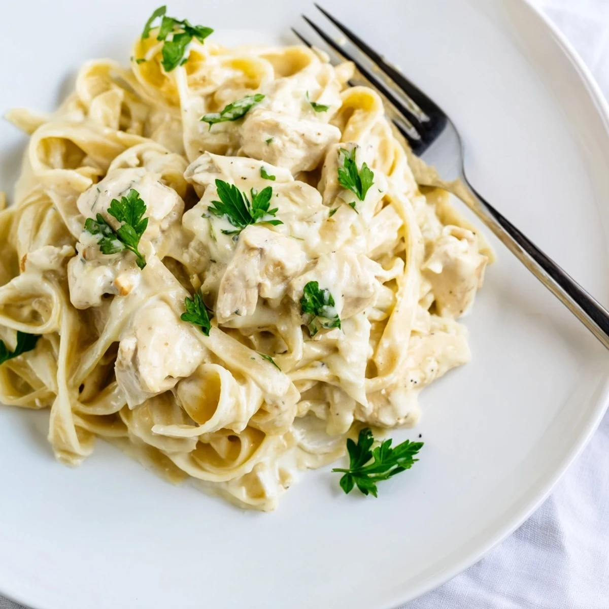 Steaming bowl of Instant Pot Chicken Alfredo garnished with fresh parsley and extra grated parmesan