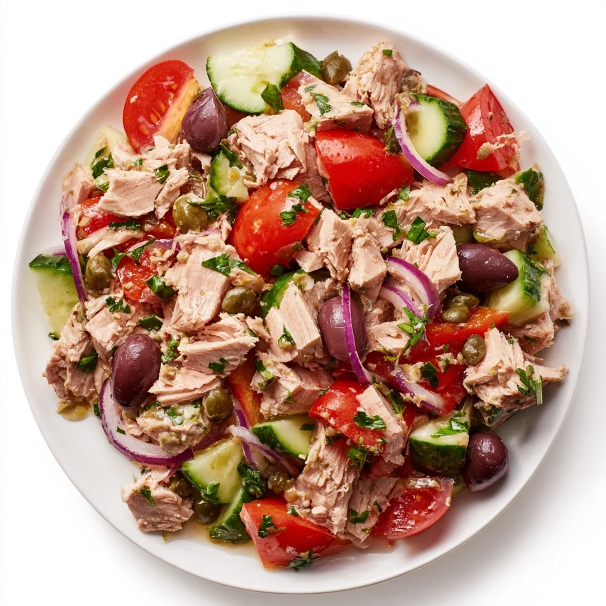 Mediterranean tuna salad in a white bowl with cherry tomatoes, olives, and fresh herbs