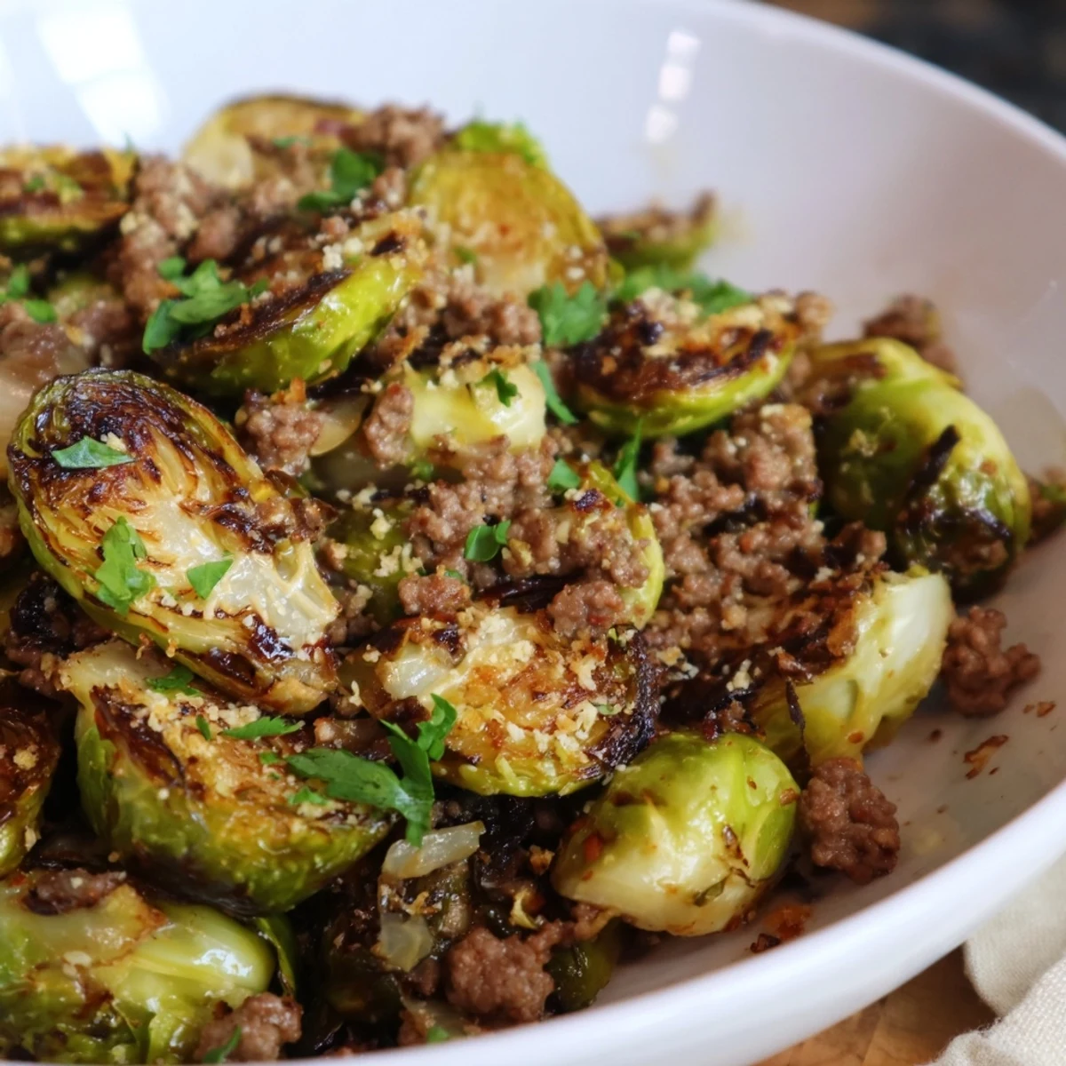 Golden brown ground beef Brussels sprouts sizzle in a cast iron skillet with caramelized onions