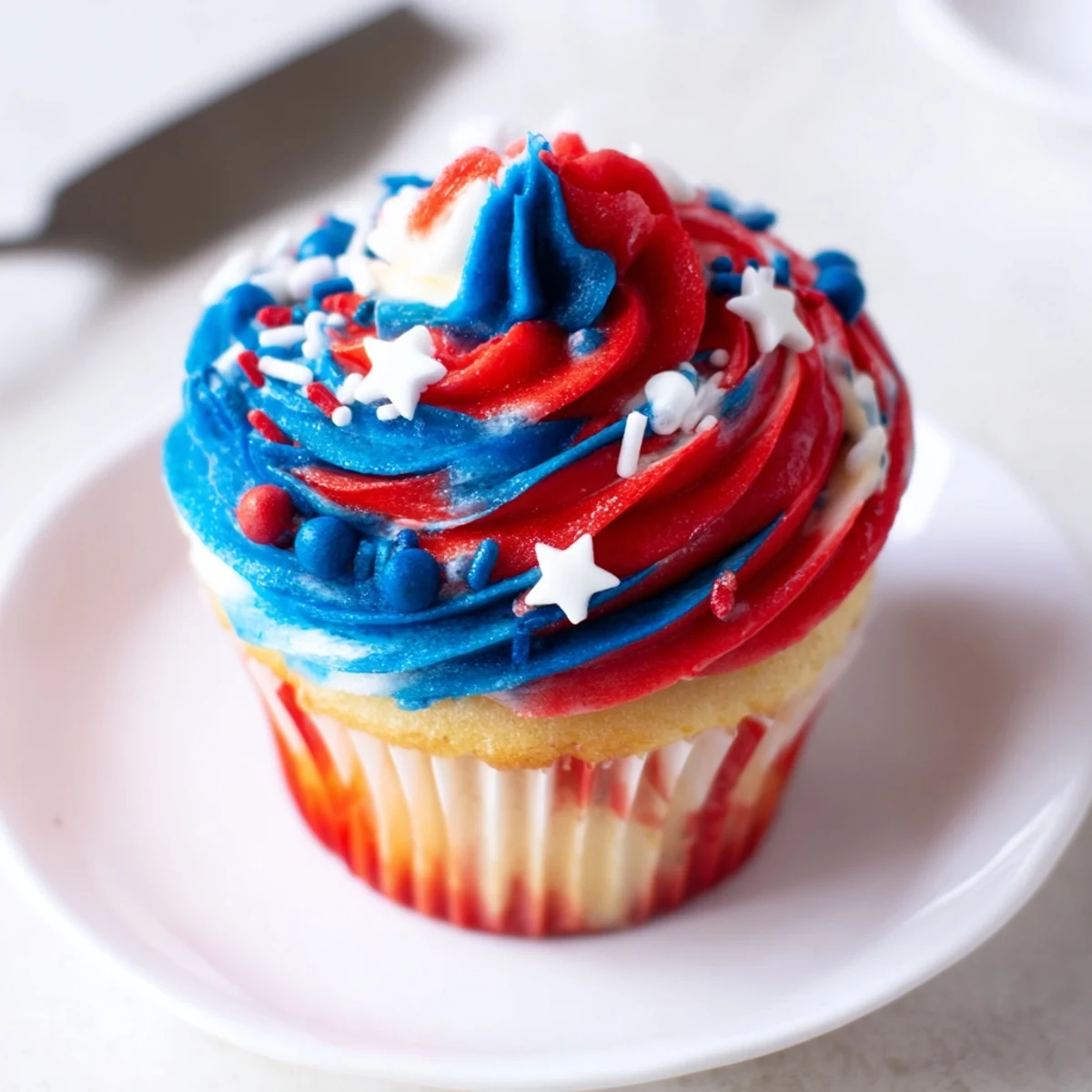 Plate of Patriotic Firework Cupcakes piped tall, sprinkled for Fourth of July celebrations