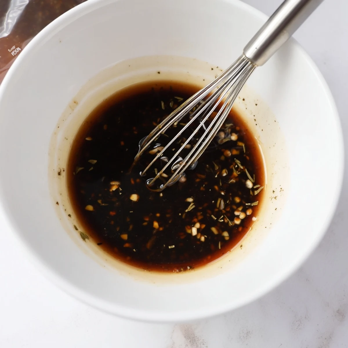 Chilled Steak Marinade in a bowl, soy and balsamic sheen, rosemary flecks.