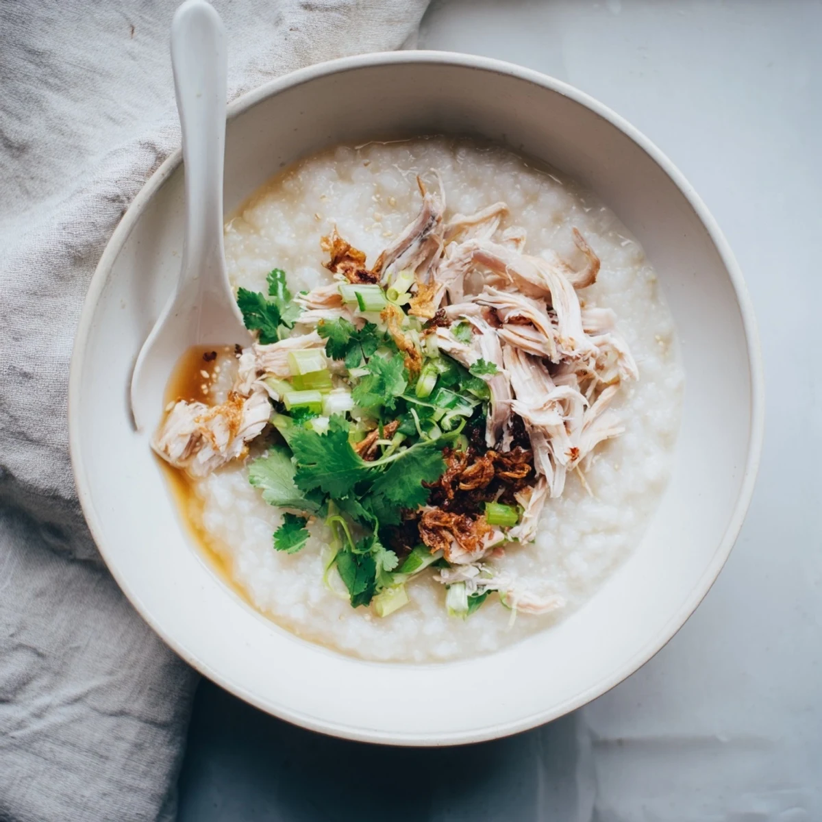 Steaming bowl of Chinese chicken congee porridge garnished with cilantro and fried shallots